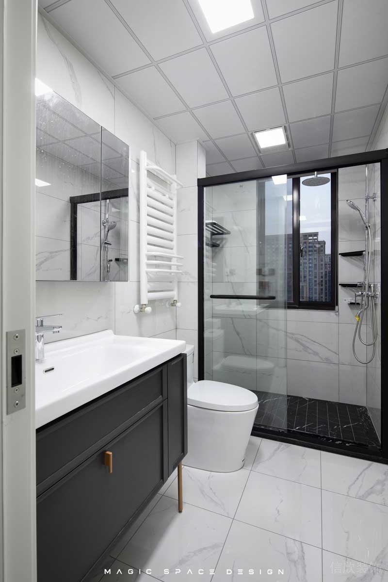 白色的大理石磚面主衛空間黑色邊框的淋浴拉門，搭配上深黑的防滑地磚。